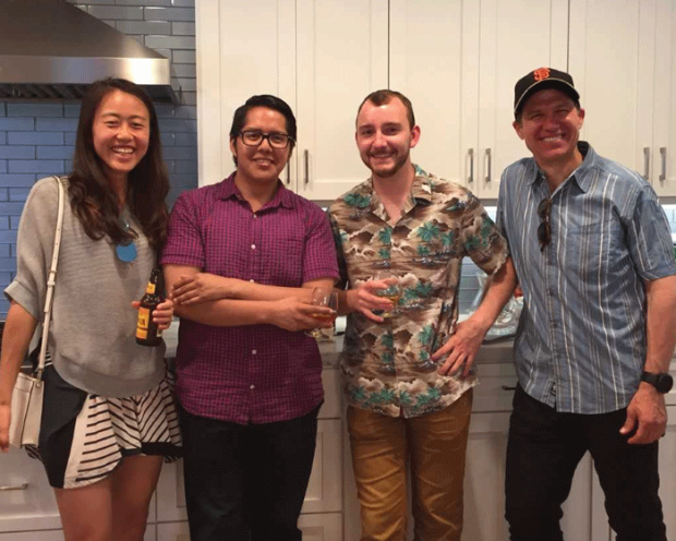 photo of four people standing together and smiling in a kitchen