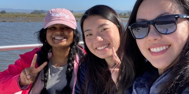 Three students on a boat smiling at the camera