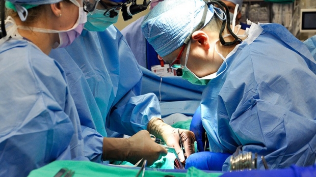 three surgeons in blue scrubs in operating room