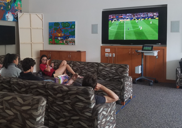 Students on couches watching soccer on tv