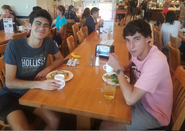 Two students sitting at table with food in dining hall