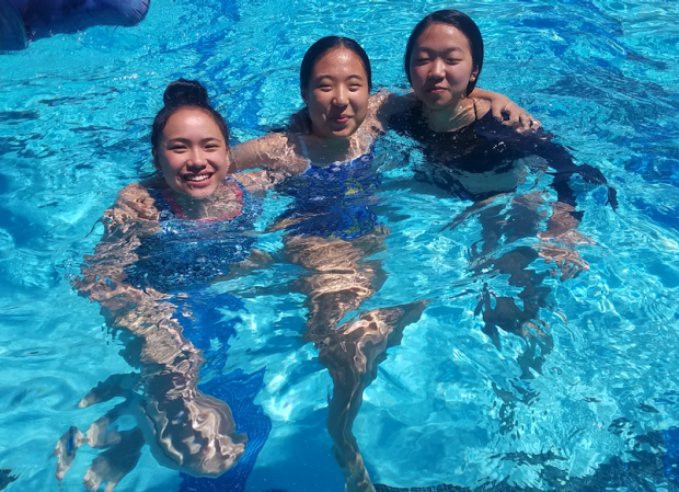 Three girls link arms in swimming pool