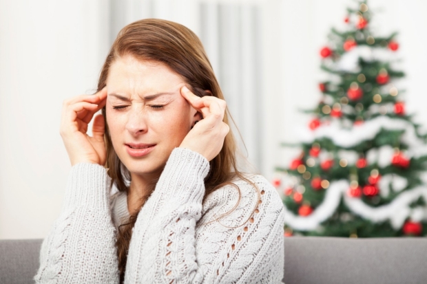 Woman with headache in front of Christmas tree