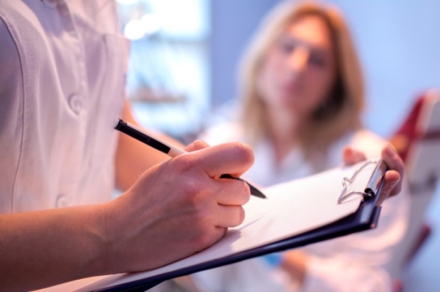 Image of medical professional writing information about patient