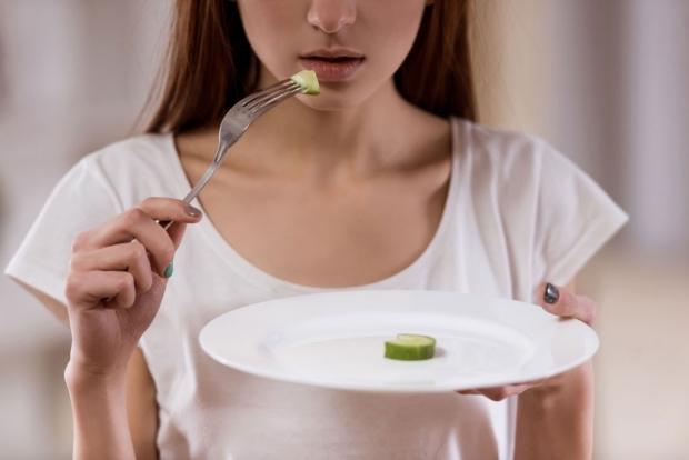 Girl eating a small piece of cucumber from a plate