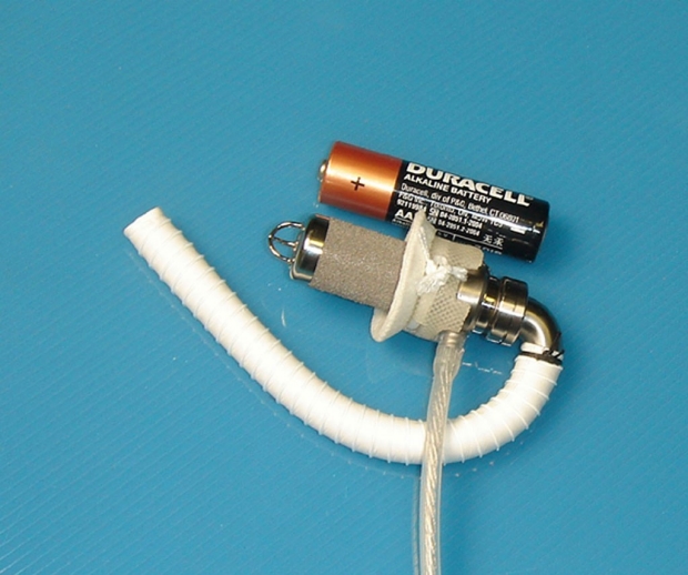 Small heart pump for children next to a AA-size battery