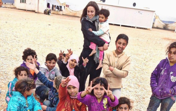 Young woman standing in a crowd of children who are Syrian refugees