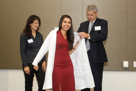Student Stephanie Kabeche puts on lab coat 