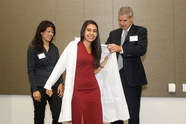 Student Stephanie Kabeche puts on lab coat