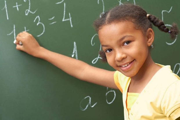 Happy young girl doing math on a chalkboard