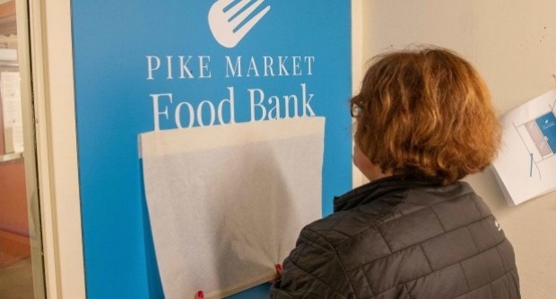 A volunteer helps improve the signage at Pike Place Market in Seattle.