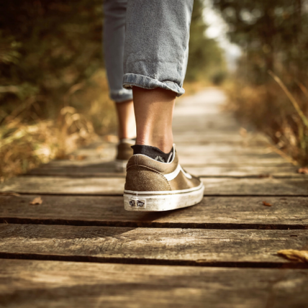 Person walking on wooden walkway in brown shoes
